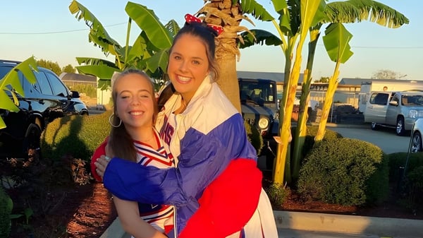 Zwei Frauen umarmen sich vor tropischen Pflanzen auf dem Gelände der Evangel Christian Academy.