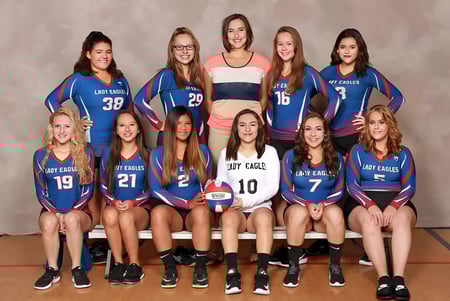 Eine Gruppe junger Volleyballspielerinnen der Evangel Christian Academy posiert in blauen und weißen Uniformen im Studio.