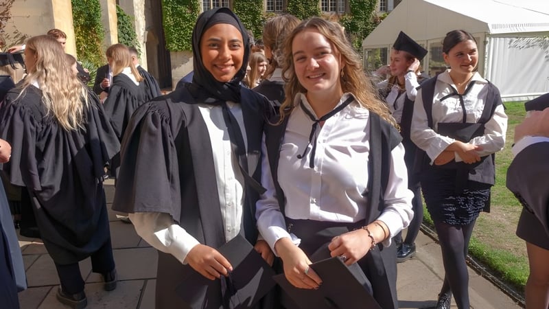 Eine Gruppe junger Absolventinnen in Abschlusskleidung auf dem Campus des Exeter College.
