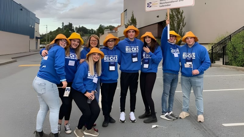 Eine Gruppe Schüler der Exploits Valley High School steht vor einer Baustelle mit blauen Hemden und Schutzhelmen.