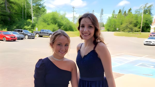 Zwei Schülerinnen der Exploits Valley High School posieren gemeinsam in formeller Kleidung in einem Park.