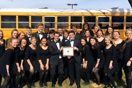 Eine Gruppe von Schülerinnen und Schülern der Fabius Pompey High School posiert vor einem gelben Schulbus.