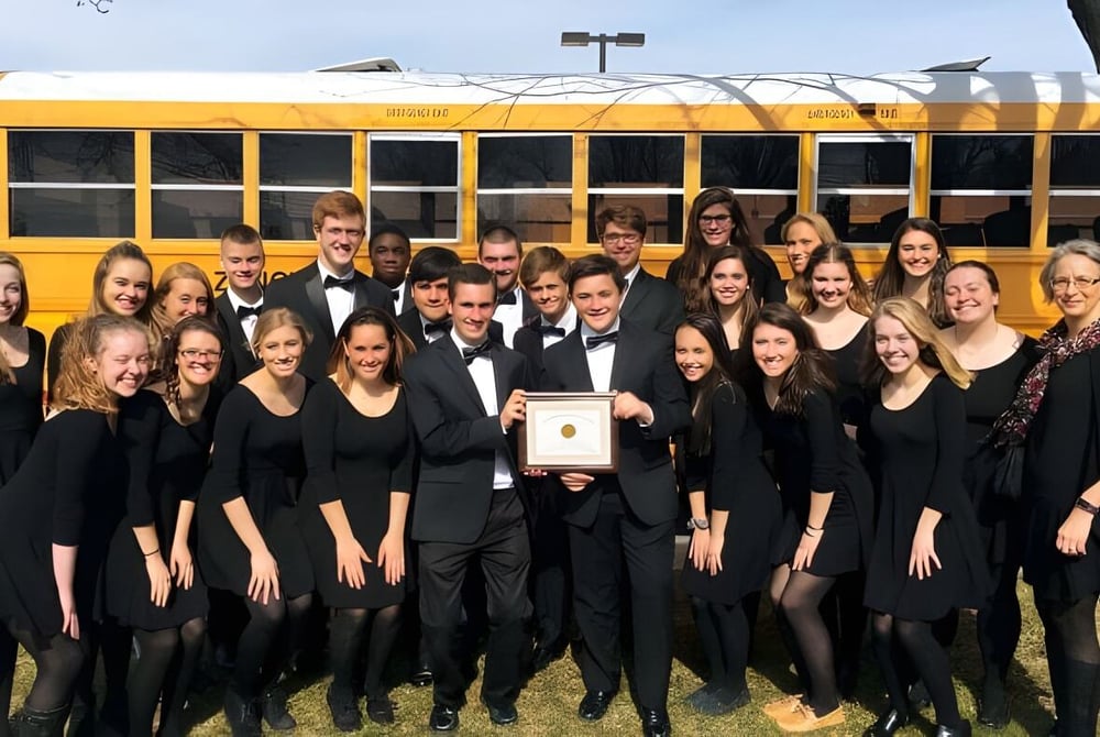 Eine Gruppe von Schülerinnen und Schülern der Fabius Pompey High School posiert vor einem gelben Schulbus.