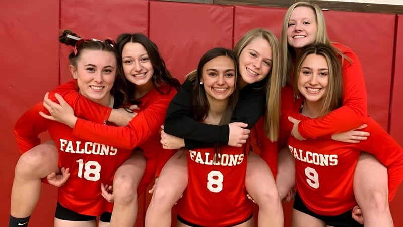 Fünf Schülerinnen der Fabius Pompey High School in roten Falcons-Sporttrikots posieren gemeinsam vor einem roten Hintergrund.