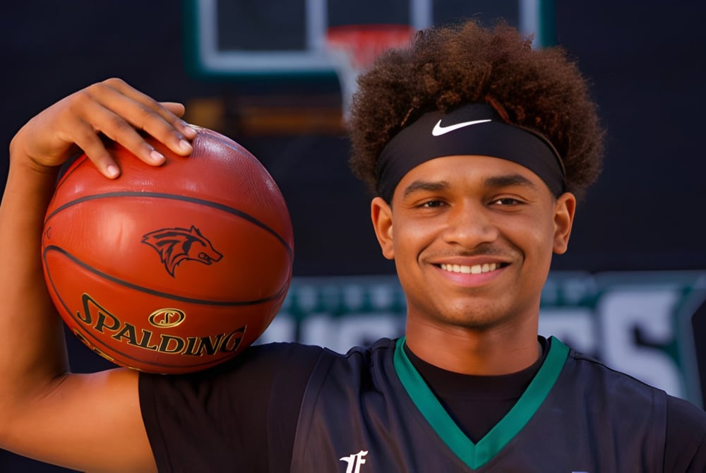 Ein Schüler der Fairmont Prep Academy hält einen Basketball vor dem Basketballfeld und lächelt.