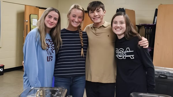 Vier Schülerinnen und Schüler stehen lächelnd in einem Schulflur der Faith Christian Academy in Pennsylvania.