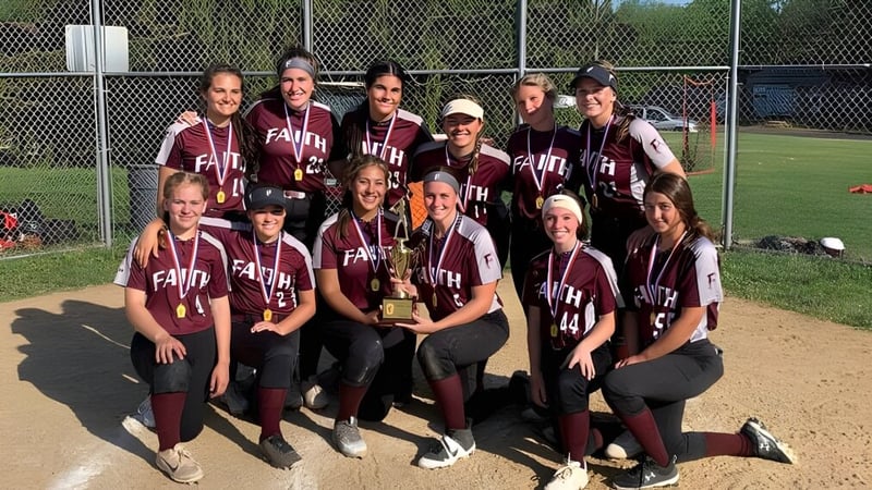 Eine Gruppe junger Softballspielerinnen der Faith Christian Academy (PA) posiert auf dem Baseballfeld vor einem Maschendrahtzaun.