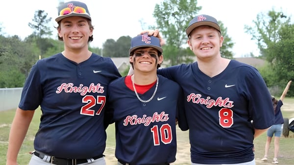 Drei Schüler der Faith Christian School in Baseballuniformen stehen gemeinsam auf einer Wiese im Freien.