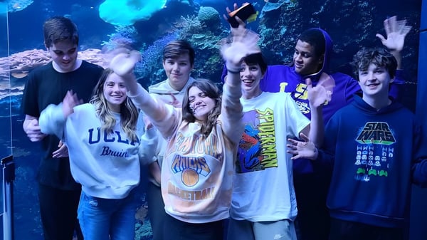 Eine Gruppe Schüler der Faith Christian School posiert vor einem Unterwasserbild mit farbenfrohen Korallen und Meereslebewesen.