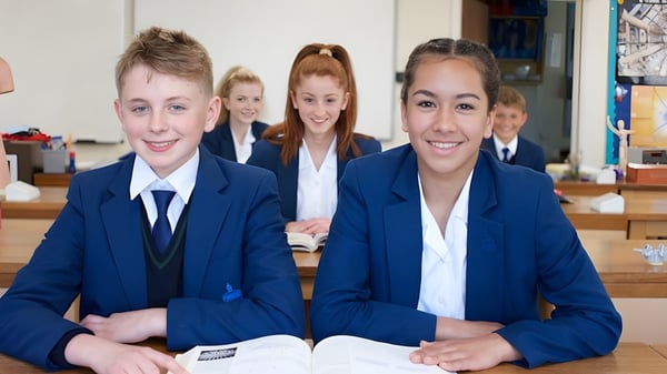 Eine Gruppe lächelnder Schüler in Schuluniform sitzt im Klassenraum der Farlington School an ihren Tischen.