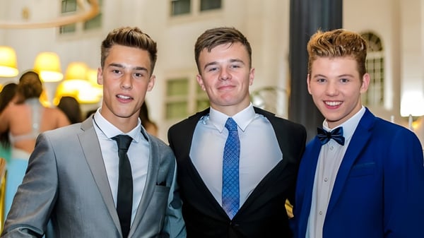 Drei junge Männer in formeller Kleidung posieren gemeinsam bei einer Veranstaltung auf dem Campus der Farringtons School.