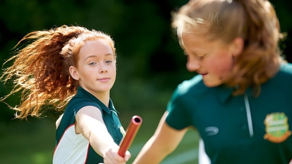 Zwei Schülerinnen der Farringtons School unterhalten sich draußen vor grünem Hintergrund.