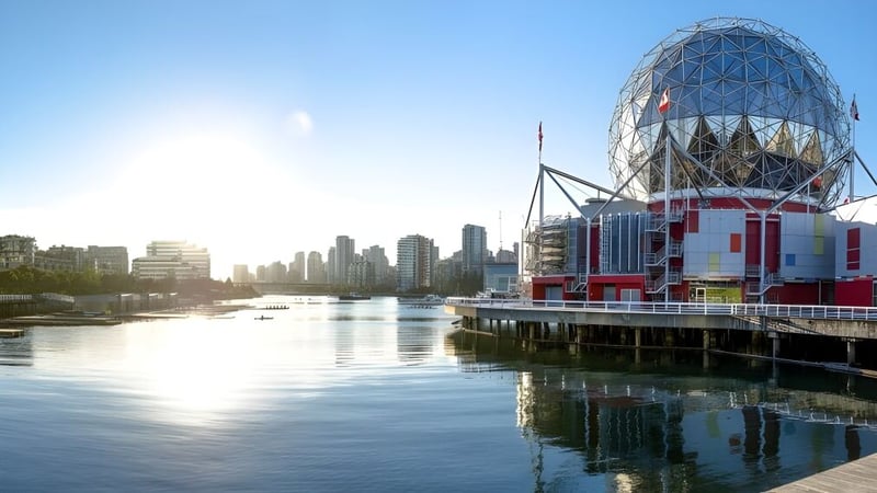 Das moderne Gebäude der Father Lacombe High School mit einer eiförmigen Glas- und Stahlkonstruktion steht auf einem Pier an einem ruhigen Gewässer.