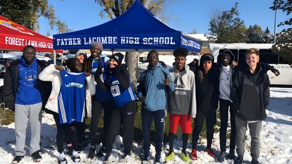 Schüler der Father Lacombe High School stehen im Winter vor einem blauen Zelt mit Schul-Logo in verschneiter Landschaft.