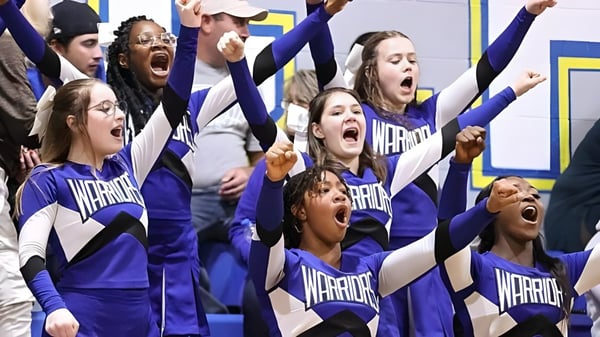 Grupp Cheerleader der Fayetteville Christian School treten in einheitlichen lila Uniformen auf einem Sportplatz auf.
