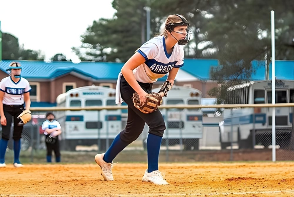 Eine Schülerin der Fayetteville Christian School steht auf dem Baseballfeld mit Baseball-Diamond und Gebäuden im Hintergrund.