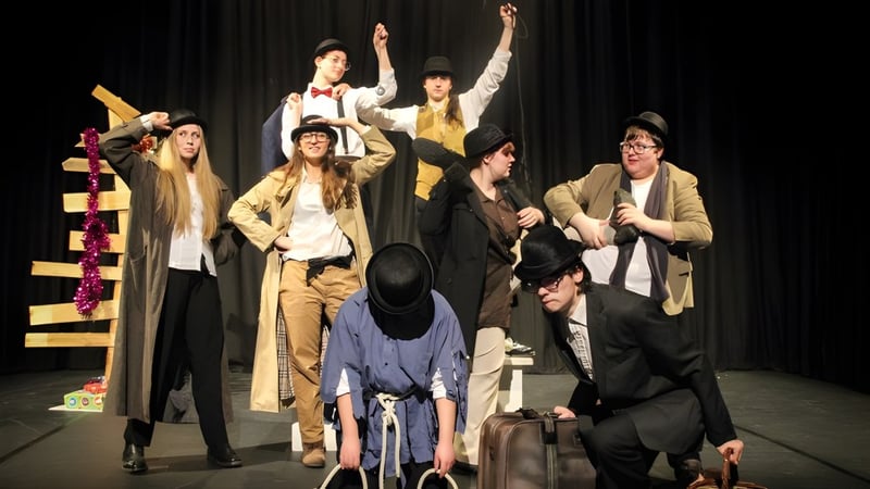 Eine Gruppe von Darstellern in bunten Kostümen auf der Bühne der Ferndown Upper School bei einer Aufführung.