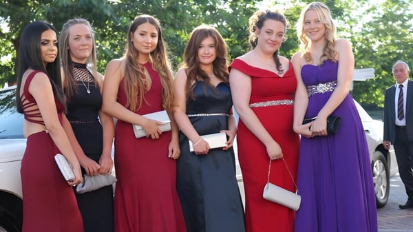 Eine Gruppe Schülerinnen der Ferndown Upper School steht in formeller Kleidung vor einem Auto vor grünem Hintergrund.