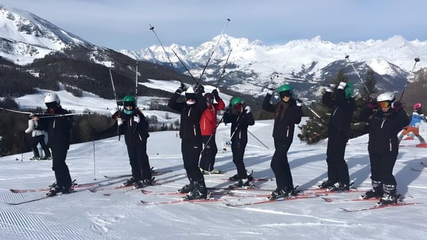 Eine Gruppe von Schülern der Ferndown Upper School steht auf einem schneebedeckten Abhang mit Bergen im Hintergrund.