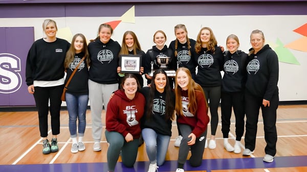 Eine Gruppe junger Athletinnen posiert in Sportuniformen in der Turnhalle der Fernie Secondary School.