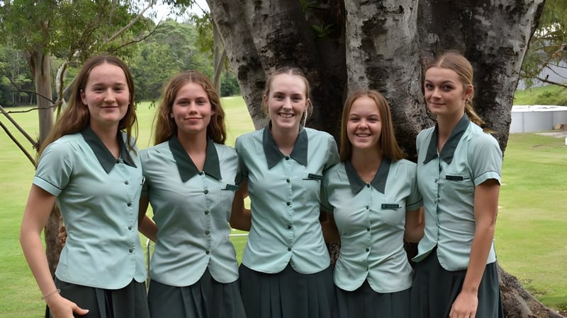 Eine Gruppe von fünf Schülerinnen der Ferny Grove State High School steht vor einem Baum mit dichtem Laub.