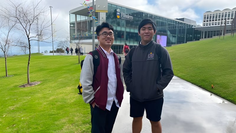 Zwei Schüler stehen vor einem modernen Gebäude auf dem Campus der Findon High School mit einer Rasenfläche im Hintergrund.