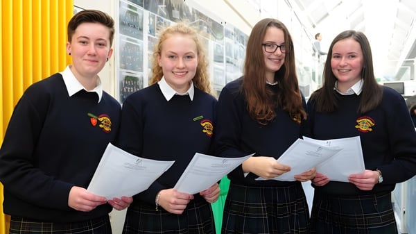 Vier Schülerinnen und Schüler im Flur des Fingal Community College tragen Schuluniformen und halten Papiere.