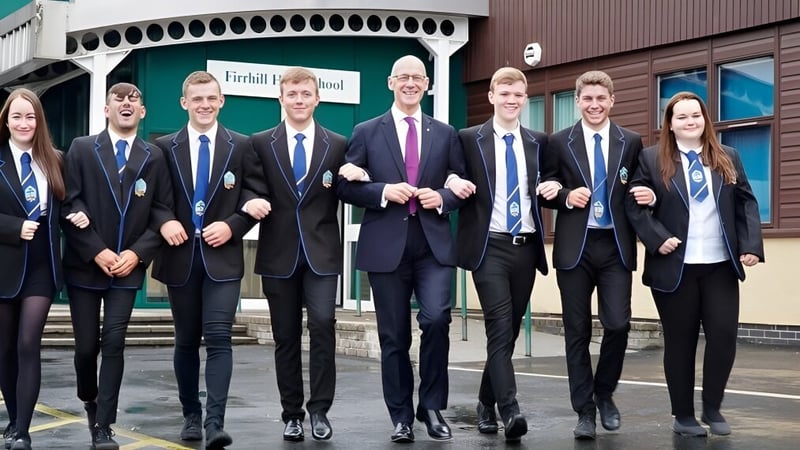 Eine Gruppe Schülerinnen und Schüler steht vor einem Gebäude der Firrhill High School.