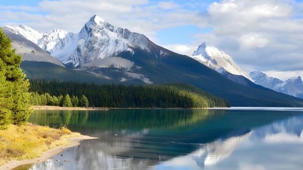 Ein ruhiger, smaragdgrüner See mit schneebedeckten Bergen im Hintergrund, aufgenommen nahe der FJ Brennan Catholic High School.