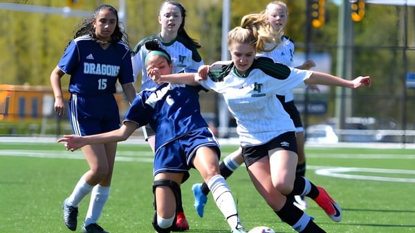 Schülerinnen der Fleetwood Park Secondary School spielen Fußball und kämpfen um den Ball auf dem Spielfeld.