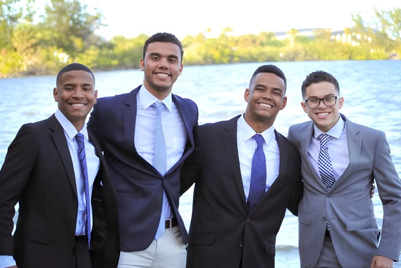 Vier Männer in formeller Kleidung stehen zusammen vor einem Gewässer auf dem Gelände der Florida Preparatory Academy.