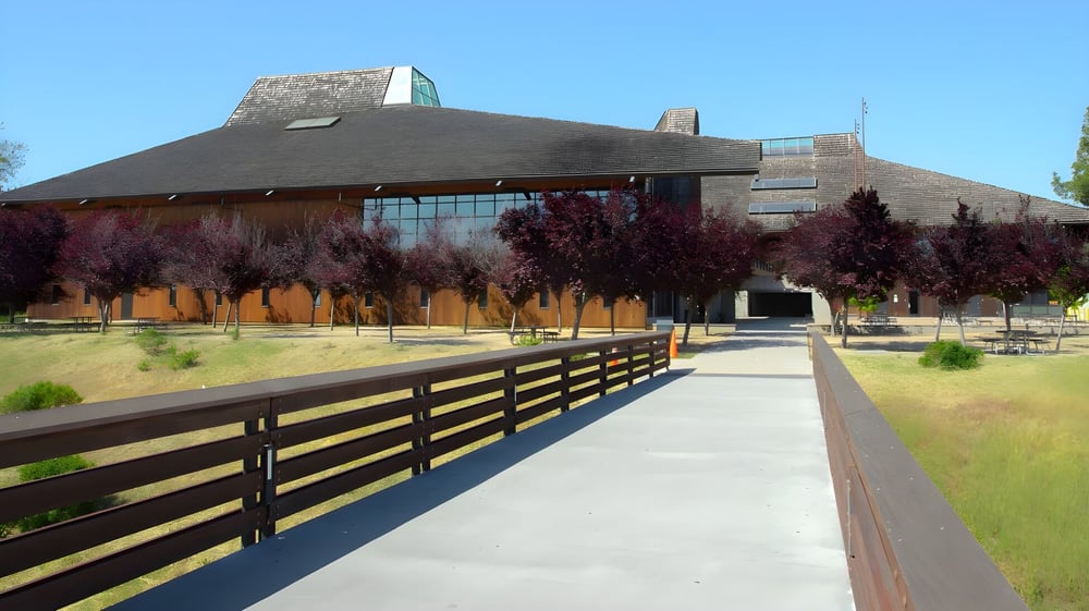 Das moderne Gebäude mit markantem Dach am Foothill College ist von einem Holzzaun und einem gepflasterten Weg umgeben.