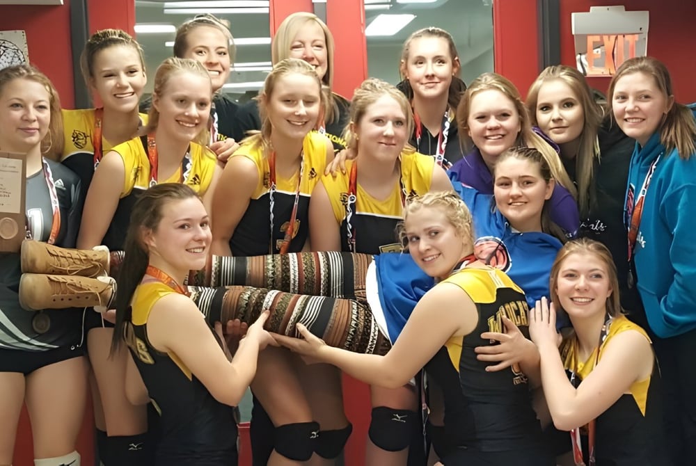 Eine Gruppe junger Schülerinnen der Forestburg School versammelt sich lächelnd in einer Sporthalle.