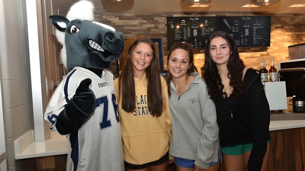 Schülerinnen der Forsyth Country Day School posieren mit dem großen Maskottchen in einem Freizeitlokal.