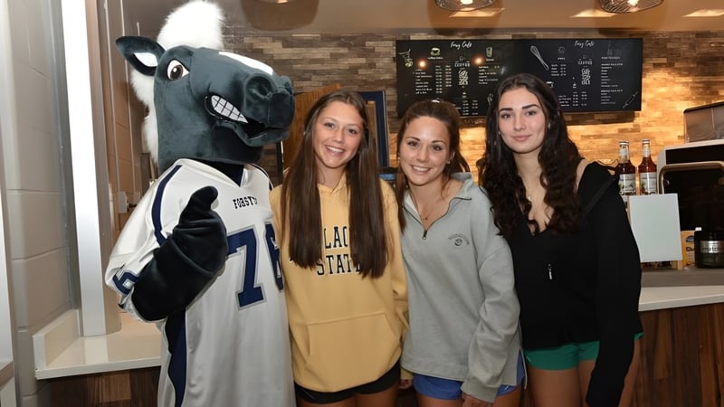 Schülerinnen der Forsyth Country Day School posieren mit dem großen Maskottchen in einem Freizeitlokal.