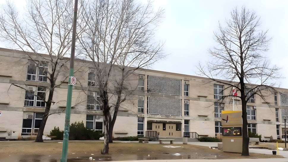 Das mehrstöckige Backsteingebäude mit kahlen Bäumen und einer Rasenfläche zeigt das Fort Richmond Collegiate.