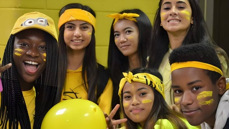 Eine Gruppe von Schülerinnen und Schülern mit gelben Accessoires posiert gemeinsam auf dem Campus der Fort Richmond Collegiate.