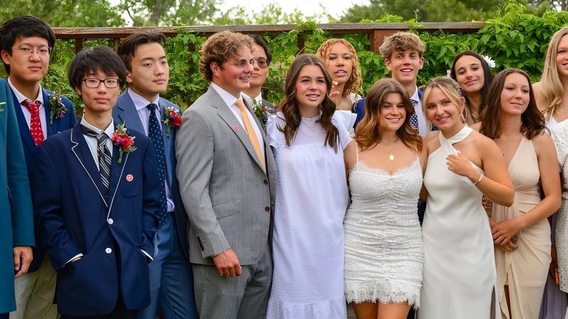 Eine Gruppe Schülerinnen und Schüler der Fountain Valley School of Colorado steht zusammen im grünen Außenbereich vor einer Holzstruktur.