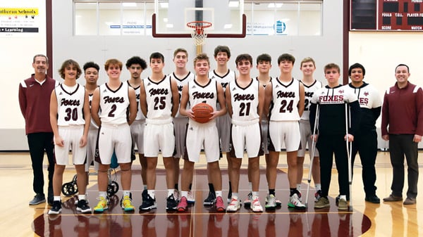 Eine Gruppe von Schülerinnen und Schülern der Fox Valley Lutheran High School posiert zusammen in der Turnhalle vor einem Basketballkorb.