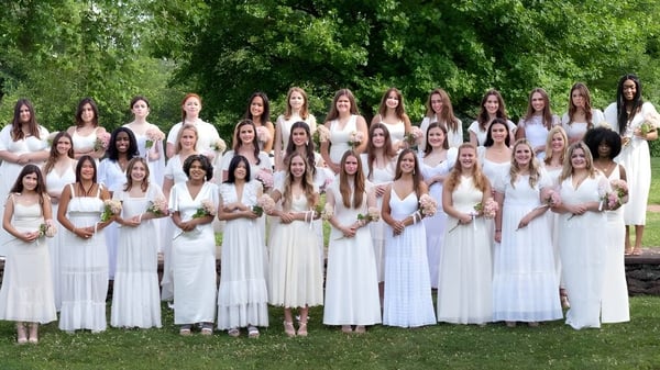 Eine Gruppe Schülerinnen der Foxcroft School trägt weißer römische Gewänder und steht gemeinsam im grünen Außenbereich.