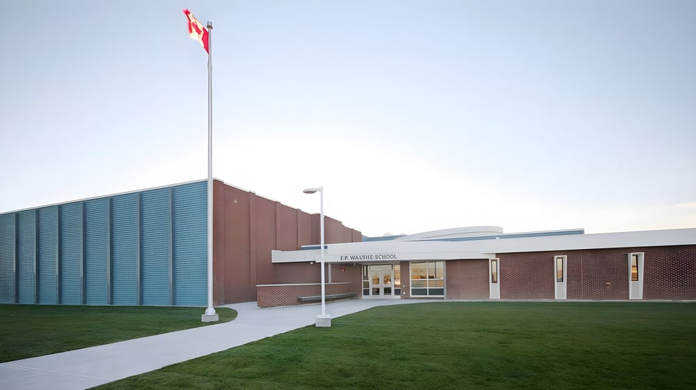 Das Backsteingebäude der F.P. Walshe School mit einer kanadischen Flagge auf dem Dach und einem Weg zum Eingang.