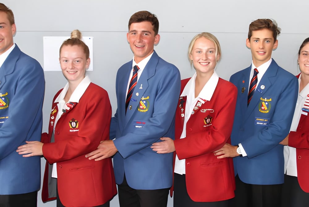 Eine Gruppe von Schülerinnen und Schülern des Francis Douglas Memorial College posiert in Abschlusskleidung in einem Studio.