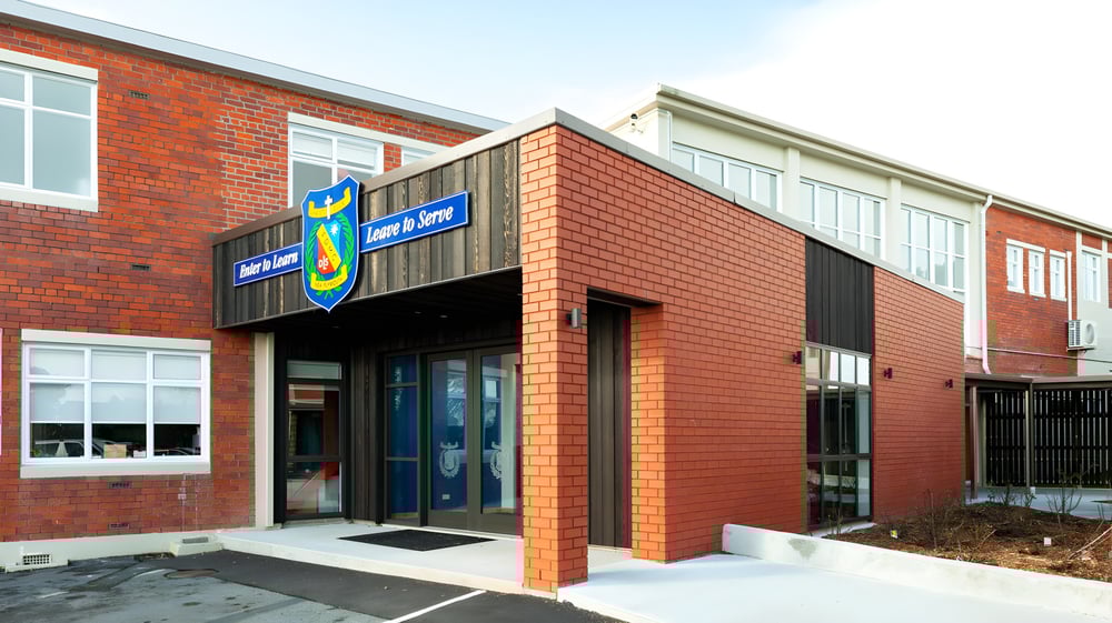 Das moderne Backsteingebäude mit großen Fenstern und einem markanten Eingang auf dem Campus des Francis Douglas Memorial College.