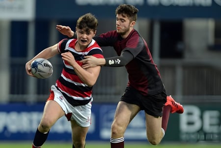 Zwei Rugbyspieler am Franciscan College Gormanston ringen auf dem Spielfeld um den Ballbesitz.