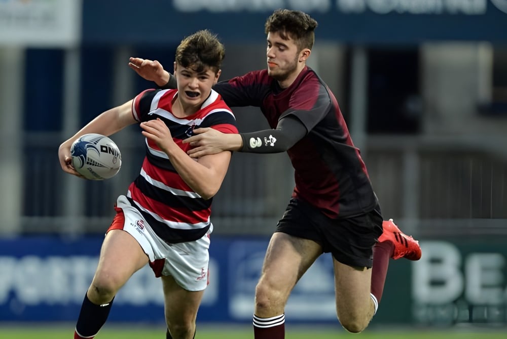 Zwei Rugbyspieler am Franciscan College Gormanston ringen auf dem Spielfeld um den Ballbesitz.