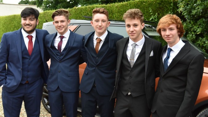 Eine Gruppe Schüler in formeller Kleidung steht vor einem Auto auf dem Gelände des Franciscan College Gormanston.
