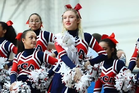 Cheerleader der Freedom Christian Academy führen eine Performance mit Pompons auf einer Bühne oder einem Spielfeld auf.