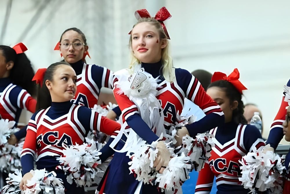 Cheerleader der Freedom Christian Academy führen eine Performance mit Pompons auf einer Bühne oder einem Spielfeld auf.