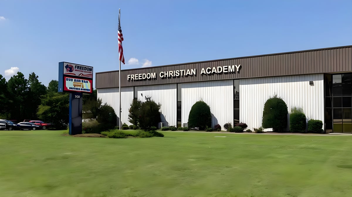 Das Gebäude der Freedom Christian Academy ist von gepflegtem Rasen und Bäumen umgeben.
