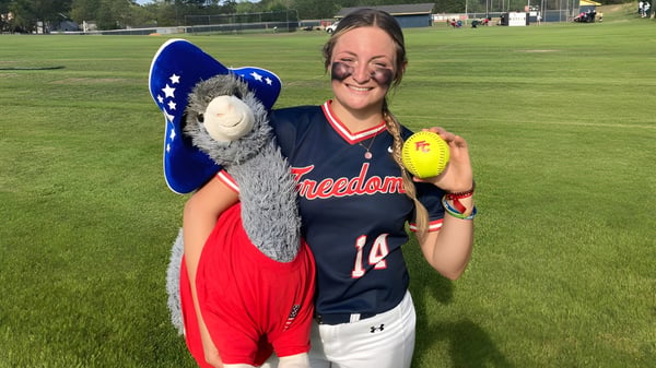 Eine lächelnde Schülerin der Freedom Christian Academy steht auf dem Softballfeld und hält einen Softball in der Hand.